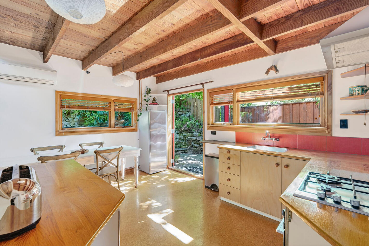 Bright kitchen/dining area with large windows, wooden beams, and natural light