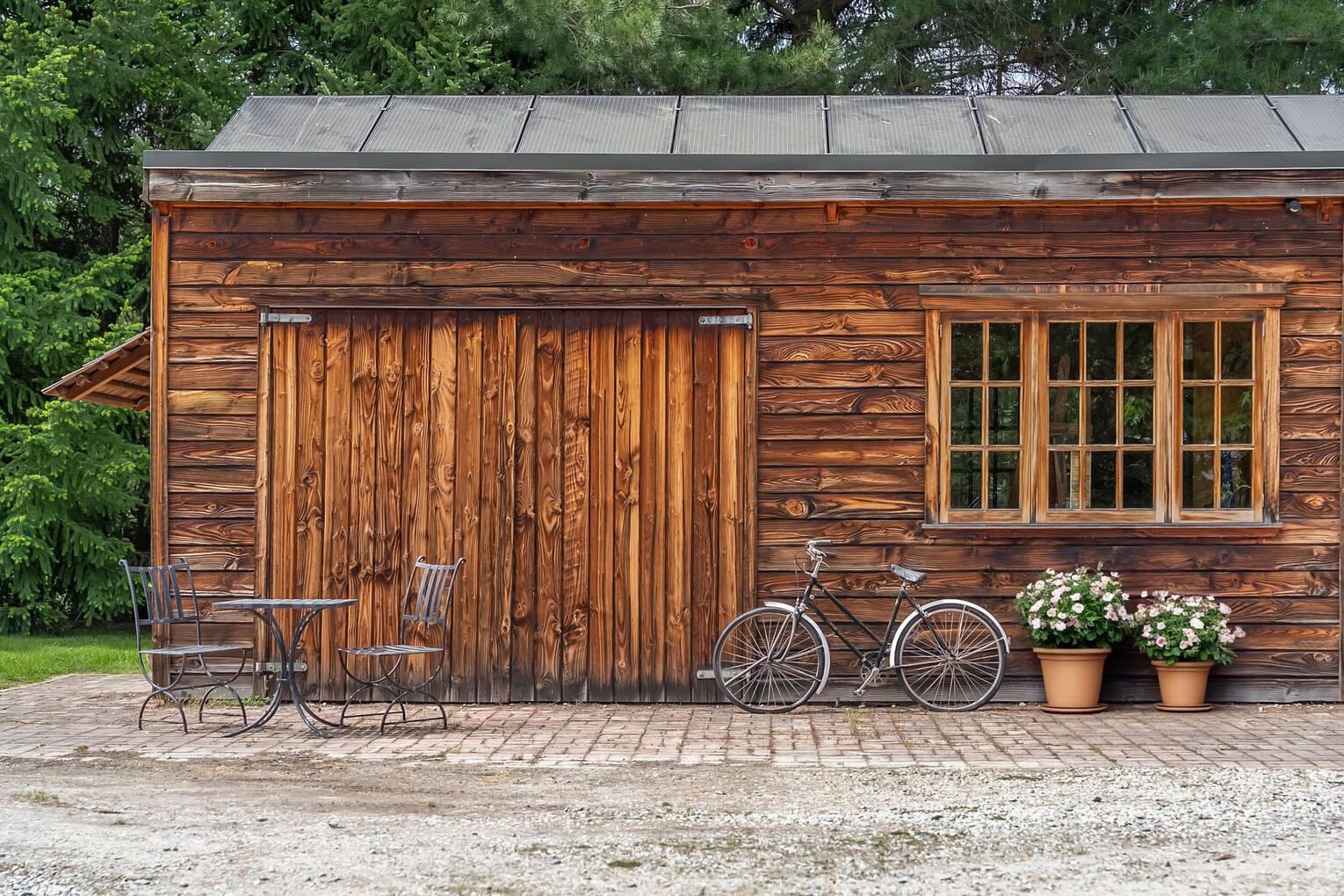 Decluttering · interior & exterior Styling · Property Staging Rustic timber outbuilding with a dark roof, small windows, and bicycles leaning against the wall