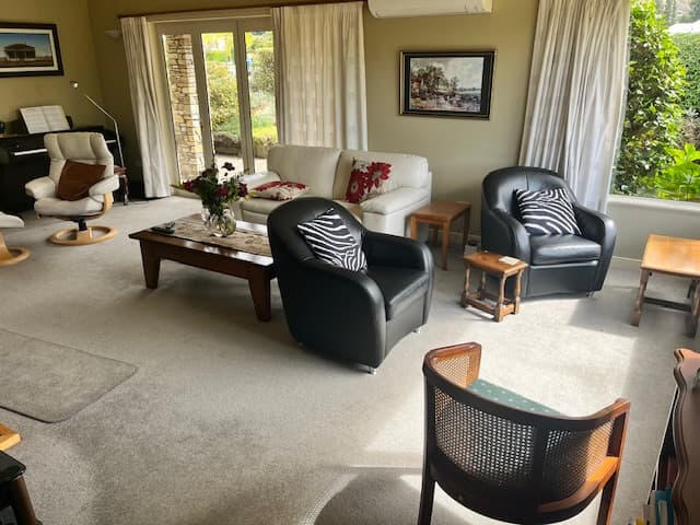 Bright bedroom with a double bed, white walls, wooden floor, and a garden-view window