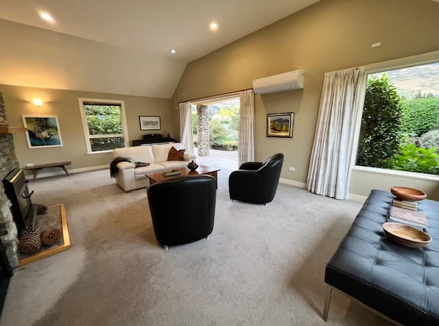 Airy bedroom with white bedding, wooden furniture, and green garden views through the window
