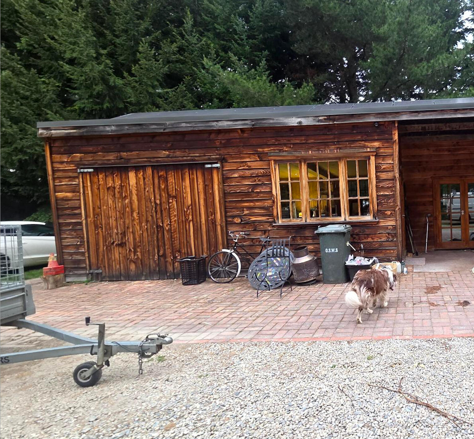 Weathered wooden barn or garage exterior with bikes parked outside on a brick driveway